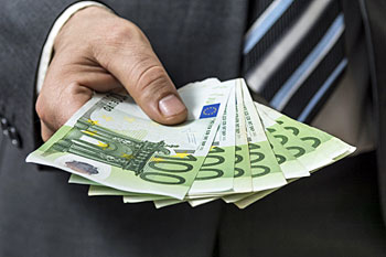 Ein Mann im Anzug hält viel Einhundert Euro Scheine aufgefächert in seiner Hand